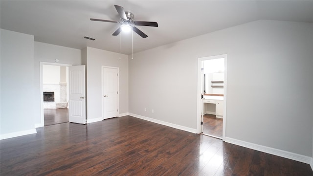 unfurnished bedroom with dark hardwood / wood-style flooring, a brick fireplace, ceiling fan, connected bathroom, and a closet