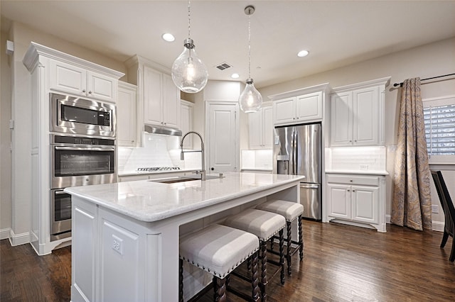 kitchen with dark hardwood / wood-style floors, white cabinetry, a kitchen island with sink, and appliances with stainless steel finishes