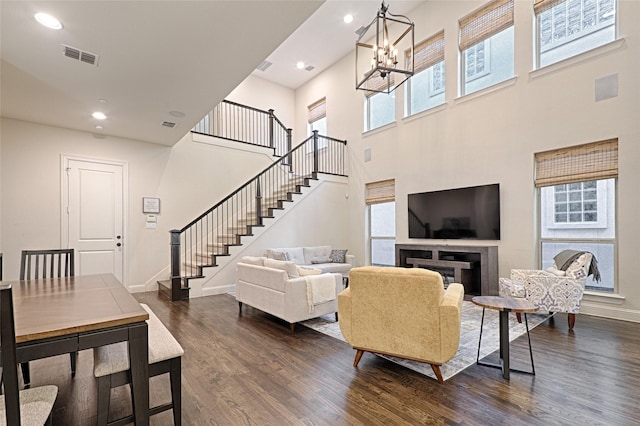 living room featuring plenty of natural light, a towering ceiling, a chandelier, and dark hardwood / wood-style floors