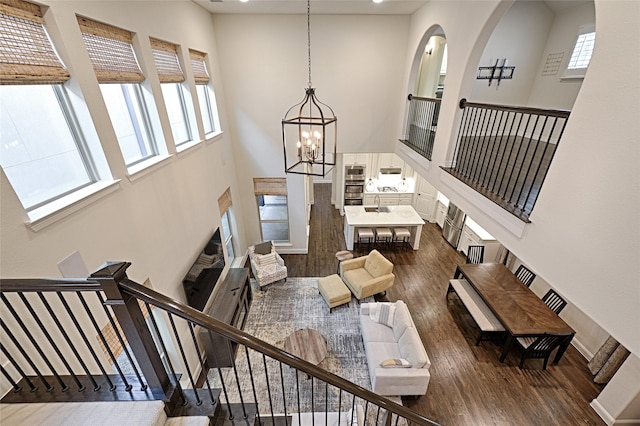 living room featuring a notable chandelier, dark hardwood / wood-style floors, and a towering ceiling