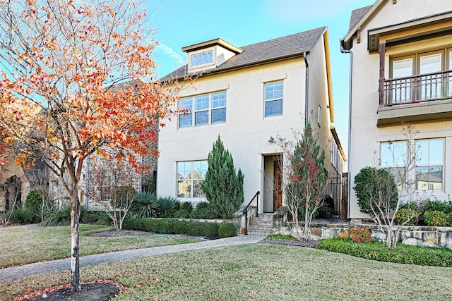 view of front facade with a balcony and a front lawn