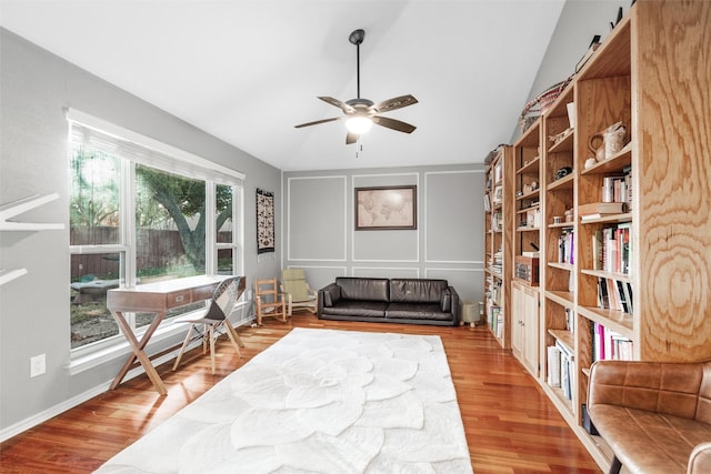 living area with a barn door, ceiling fan, vaulted ceiling, and hardwood / wood-style flooring