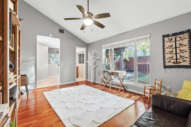 living area with hardwood / wood-style floors, high vaulted ceiling, and ceiling fan