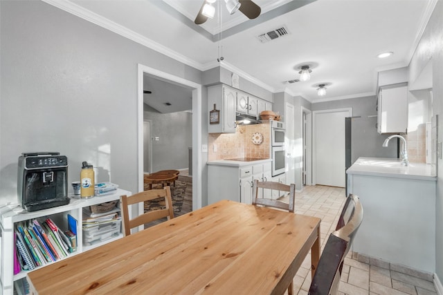 dining area featuring ceiling fan, sink, and ornamental molding