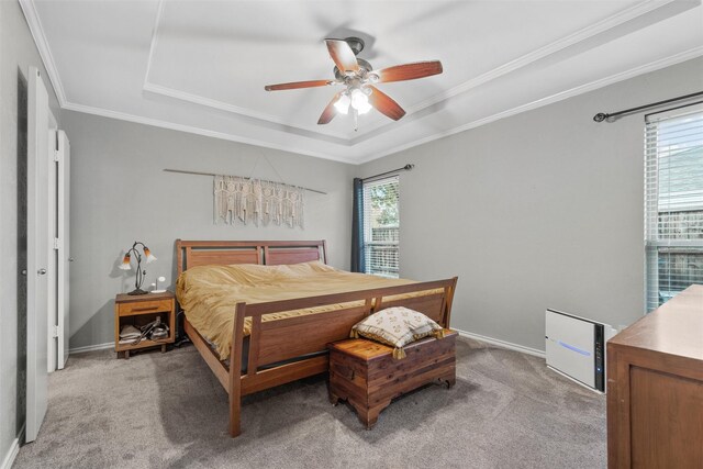 carpeted bedroom with a raised ceiling, multiple windows, ornamental molding, and ceiling fan