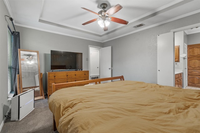 carpeted bedroom with a tray ceiling, ensuite bath, ceiling fan, and crown molding