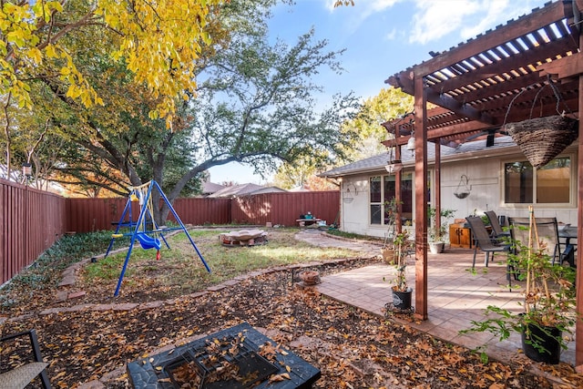 view of yard featuring a pergola, a playground, a patio, and an outdoor fire pit