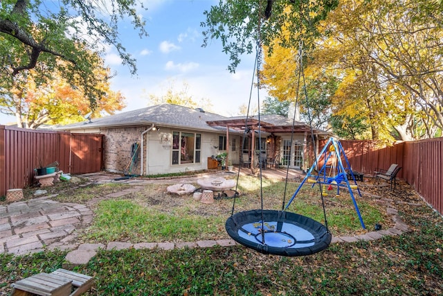 back of property featuring a playground and an outdoor fire pit