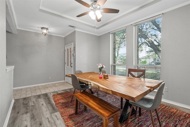 dining room featuring ceiling fan, a raised ceiling, wood-type flooring, and ornamental molding