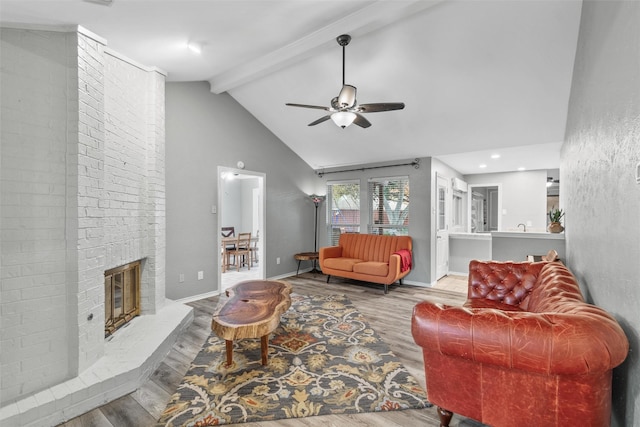 living room featuring light wood-type flooring, ceiling fan, high vaulted ceiling, beamed ceiling, and a fireplace