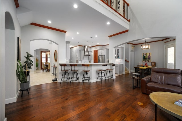 living area with stairway, baseboards, arched walkways, and wood finished floors