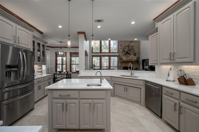 kitchen with appliances with stainless steel finishes, a center island with sink, and gray cabinetry