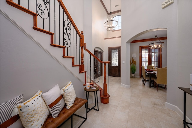 foyer with a chandelier, arched walkways, crown molding, and stairs