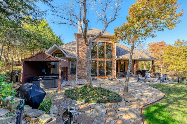 back of property featuring a shingled roof, a patio area, fence, and a hot tub