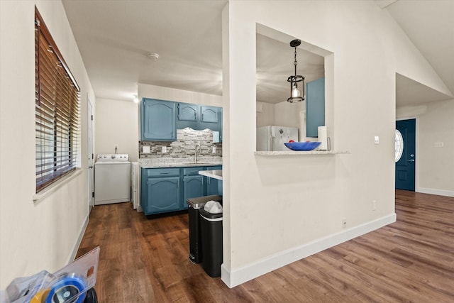 kitchen featuring sink, dark wood-type flooring, white refrigerator, decorative light fixtures, and washer / dryer