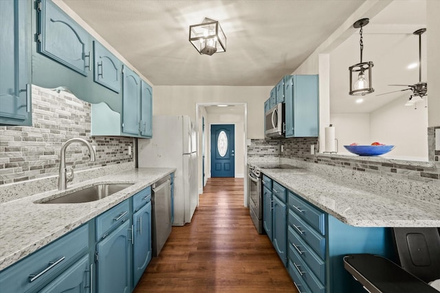 kitchen with appliances with stainless steel finishes, blue cabinets, sink, dark hardwood / wood-style floors, and hanging light fixtures