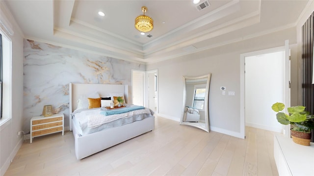 bedroom featuring light hardwood / wood-style flooring, a raised ceiling, and ornamental molding