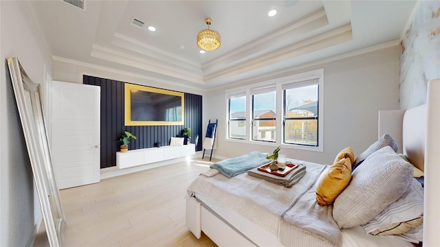 bedroom featuring light hardwood / wood-style floors, a raised ceiling, and crown molding