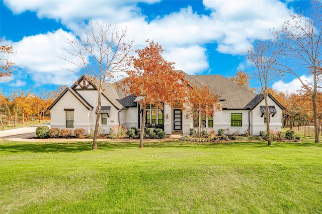 modern farmhouse with brick siding, a shingled roof, and a front lawn