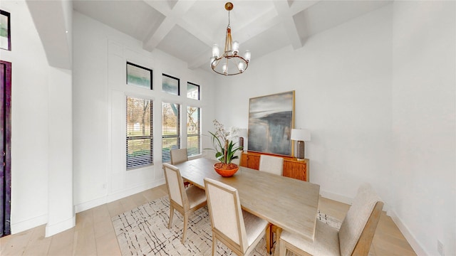 dining room featuring beamed ceiling, light hardwood / wood-style floors, coffered ceiling, and an inviting chandelier