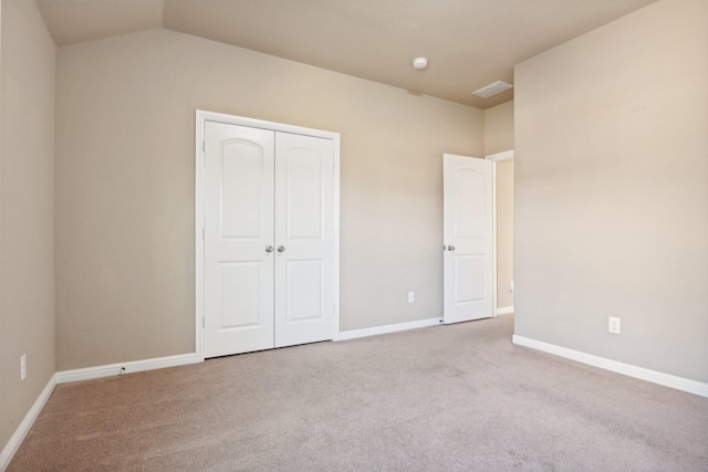 unfurnished bedroom featuring lofted ceiling, light carpet, and a closet