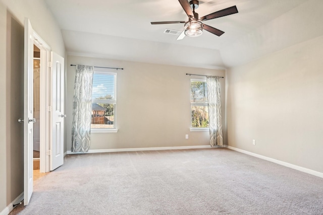 spare room featuring light carpet, vaulted ceiling, and ceiling fan