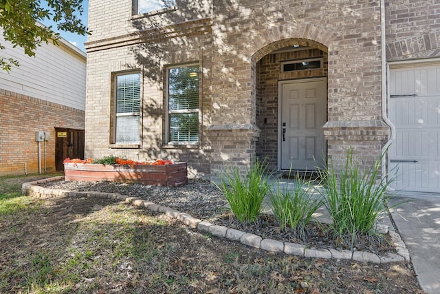 view of exterior entry with brick siding and an attached garage