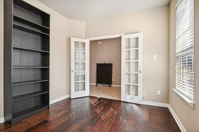 empty room with built in features, plenty of natural light, french doors, and hardwood / wood-style flooring