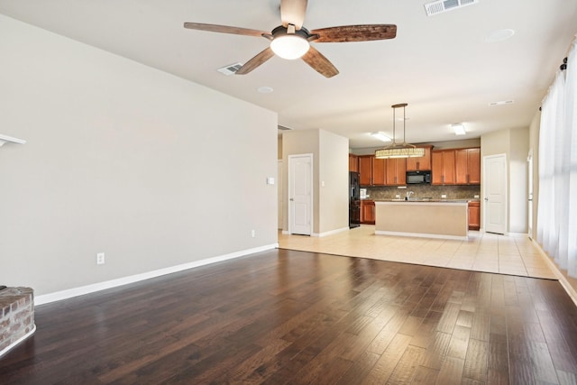 2812 Merry View Ln, Fort Worth, TX 76120 - unfurnished living room with a ceiling fan, visible vents, baseboards, and light wood-type flooring