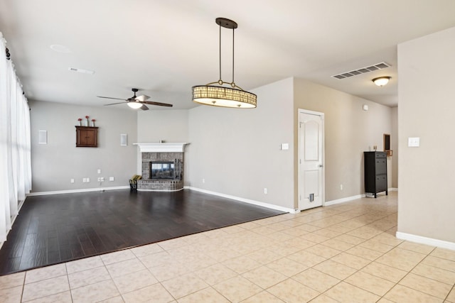 unfurnished living room featuring a fireplace, ceiling fan, light hardwood / wood-style flooring, and plenty of natural light