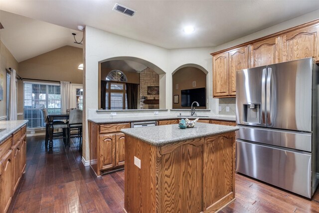 kitchen featuring appliances with stainless steel finishes, a center island, dark hardwood / wood-style floors, and vaulted ceiling