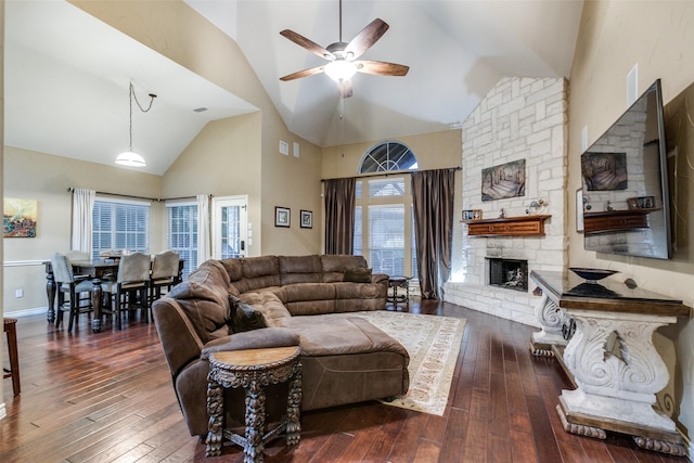 living room featuring a fireplace, ceiling fan, dark wood-type flooring, and high vaulted ceiling