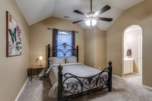 bedroom with ceiling fan, light colored carpet, connected bathroom, and vaulted ceiling