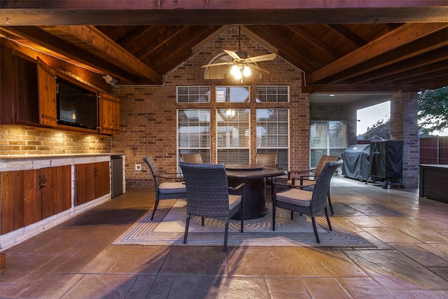 dining room with ceiling fan, beamed ceiling, brick wall, and wooden ceiling