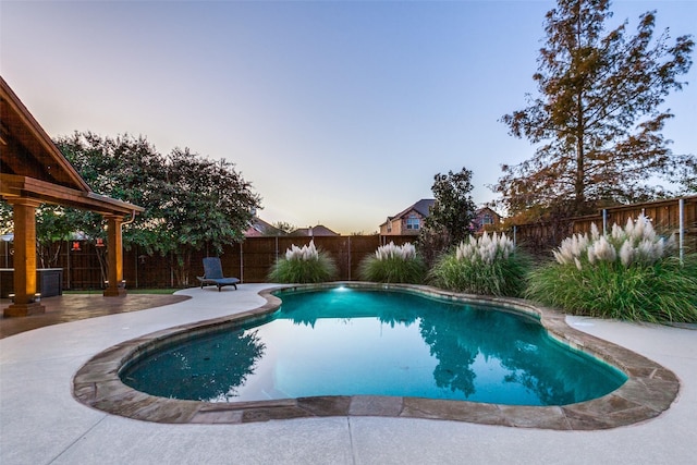 pool at dusk with a patio area