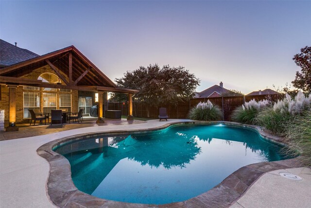 pool at dusk featuring a patio