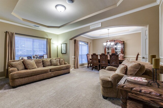 carpeted living room with a raised ceiling and ornamental molding