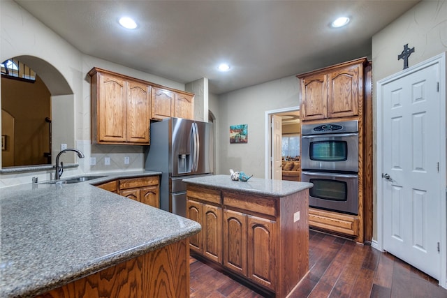 kitchen with sink, appliances with stainless steel finishes, tasteful backsplash, a kitchen island, and dark hardwood / wood-style flooring