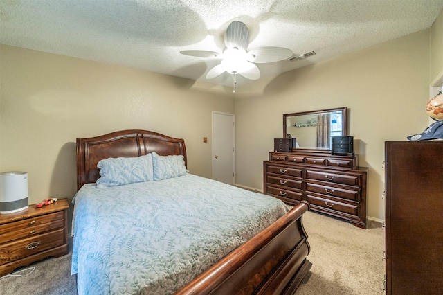 carpeted bedroom featuring ceiling fan and a textured ceiling