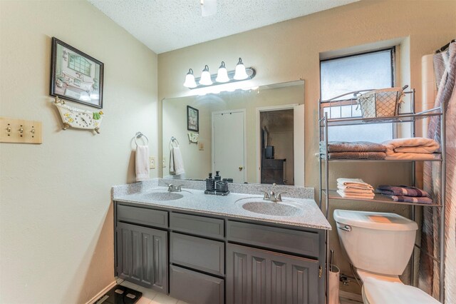 bathroom with tile patterned flooring, vanity, a textured ceiling, toilet, and walk in shower