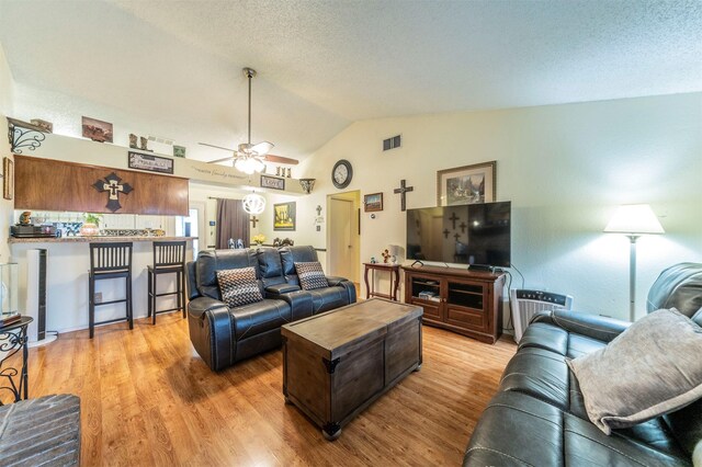 living room with lofted ceiling, ceiling fan, a textured ceiling, and light hardwood / wood-style flooring