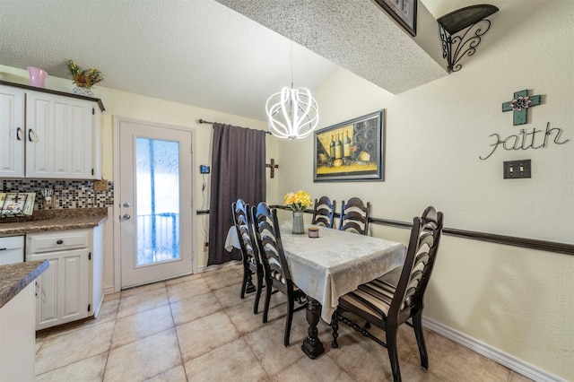 tiled dining space with lofted ceiling, a textured ceiling, and a notable chandelier