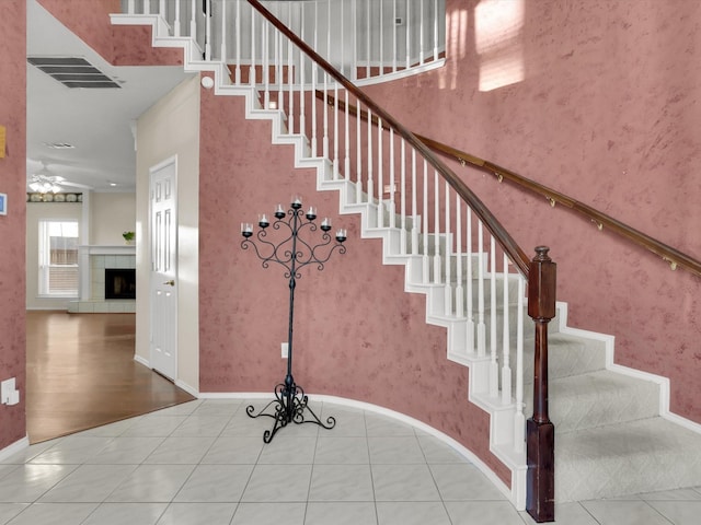 stairs featuring tile patterned flooring, ceiling fan, and a tiled fireplace