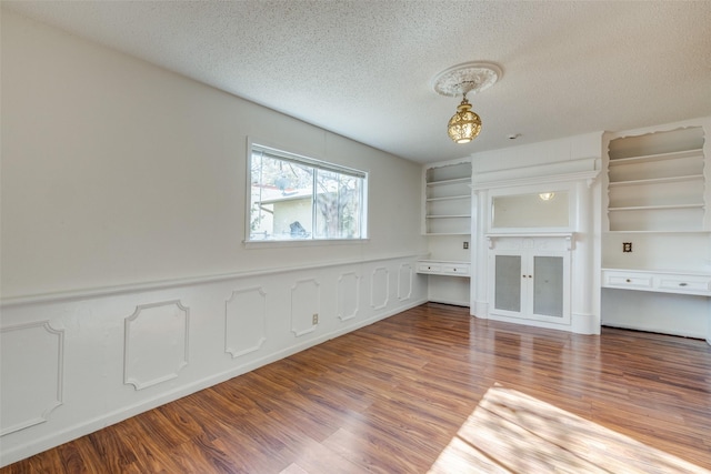 unfurnished living room with a textured ceiling and hardwood / wood-style flooring