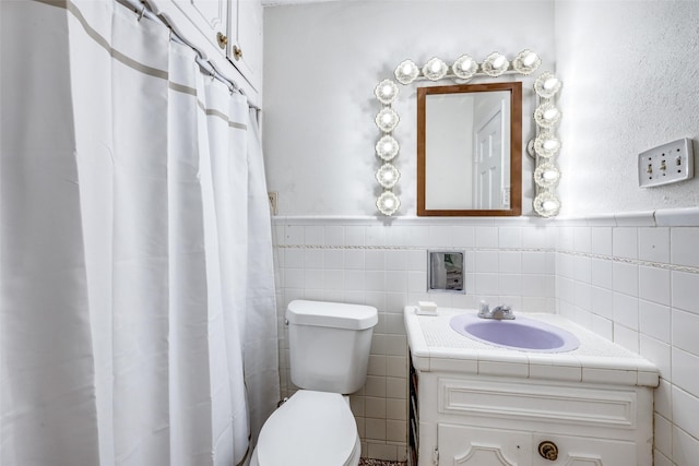 bathroom with vanity, toilet, and tile walls