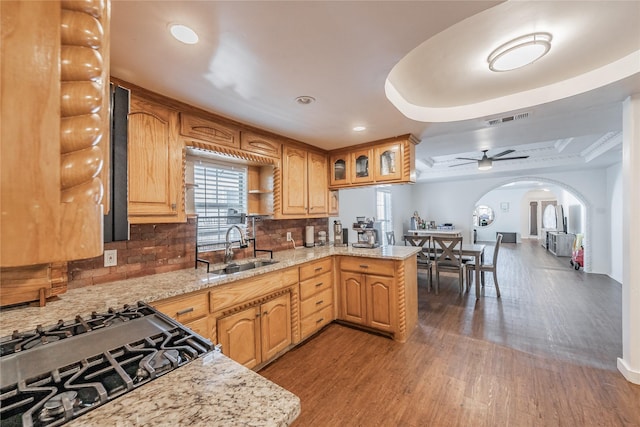 5613 Graham St, Sansom Park, TX 76114 - kitchen featuring a sink, arched walkways, wood finished floors, backsplash, and ceiling fan