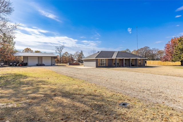 single story home featuring an outbuilding, a garage, and a front lawn