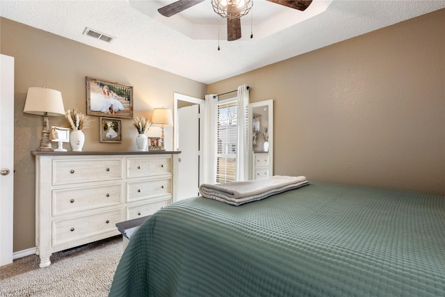 carpeted bedroom featuring a raised ceiling and ceiling fan