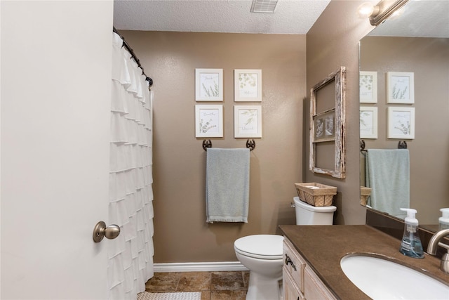 bathroom with vanity, a textured ceiling, and toilet