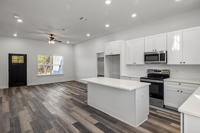 kitchen featuring white cabinets, a kitchen island, dark wood-type flooring, and appliances with stainless steel finishes